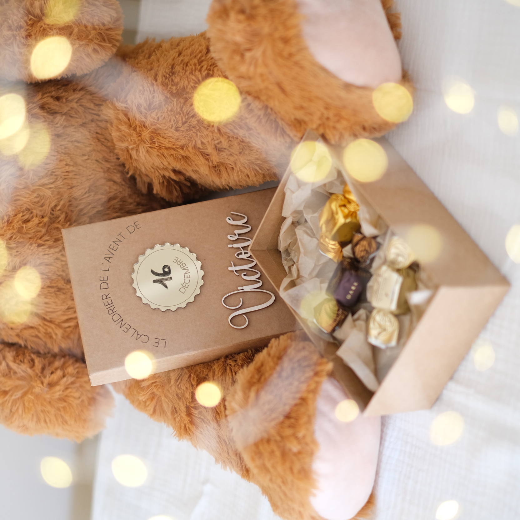 Boîte du calendrier de l’Avent ouverte devant l’ours en peluche avec des chocolats en exemple de garniture