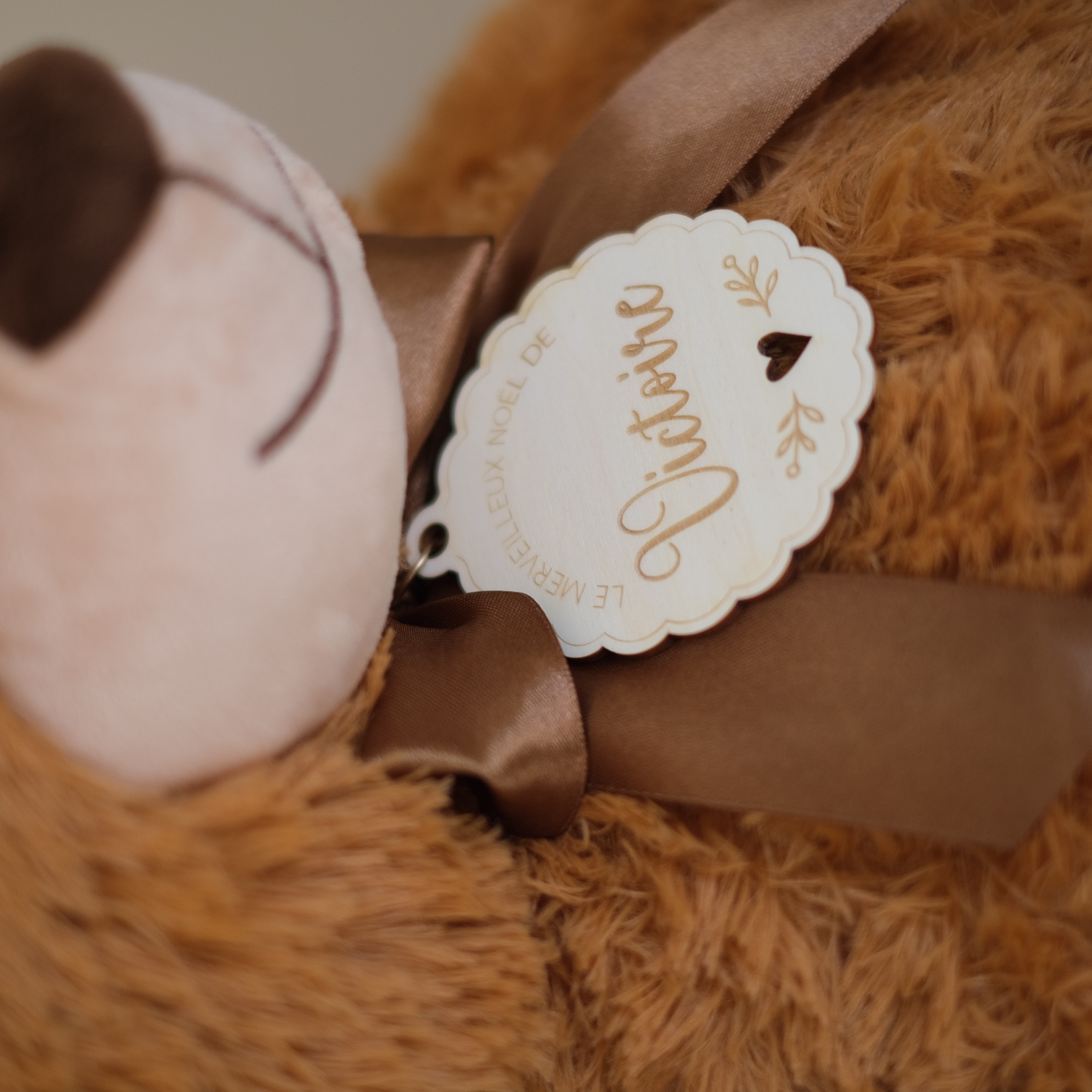 Médaille en bois au prénom de l’enfant et ruban brun sur l’ours calendrier de l’Avent